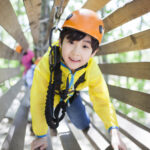 Little boy playing in tree top adventure park