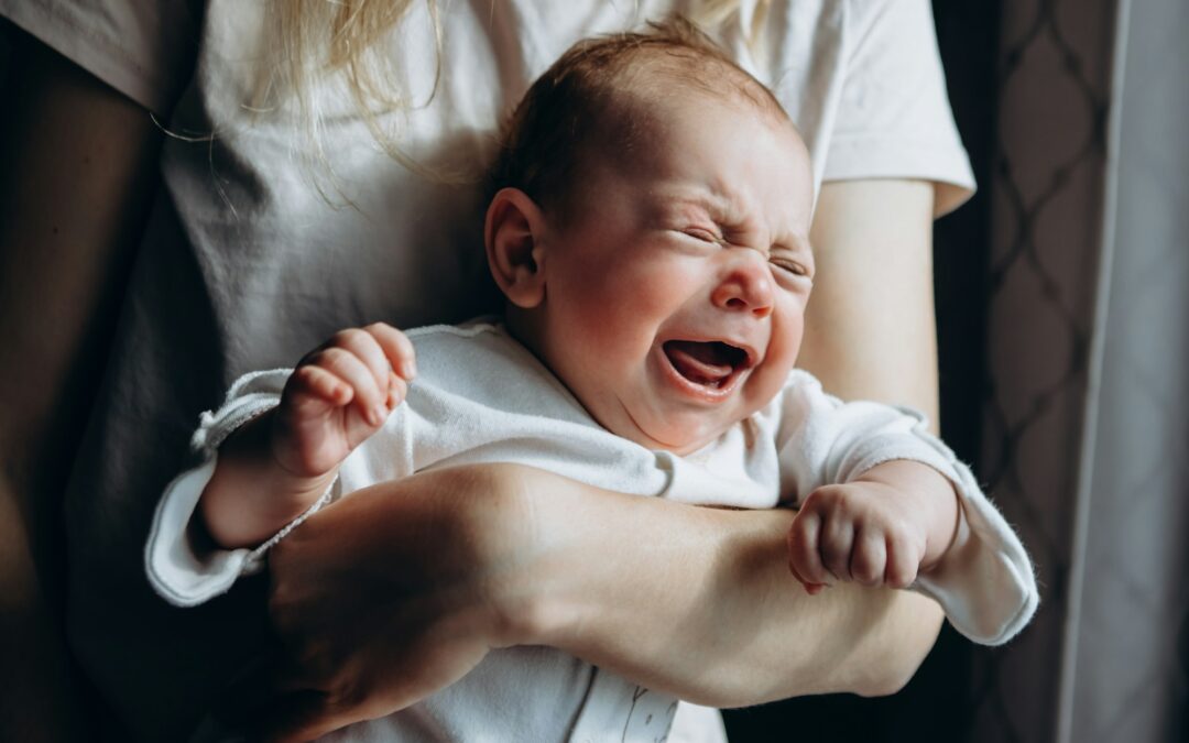 newborn baby crying in mother's arms