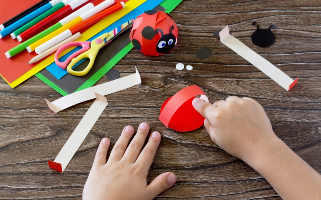 The child makes crafts out of paper ladybug.